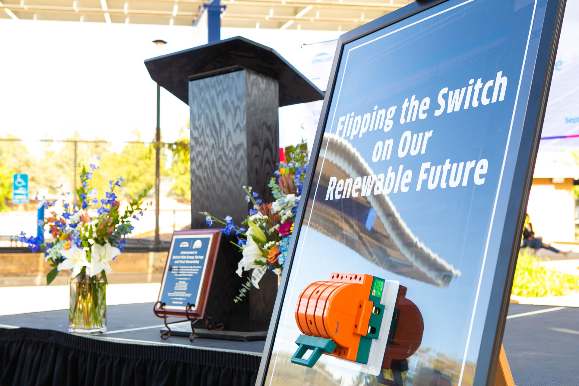Podium and sign reading “Flipping the Switch on Our Renewable Future” at an El Dorado Union High School event after project completion.